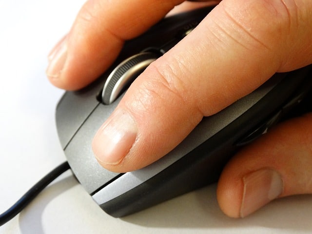 A hand clicking a computer mouse