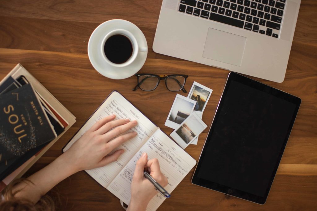 Image of a desk with a laptop, tablet and diary