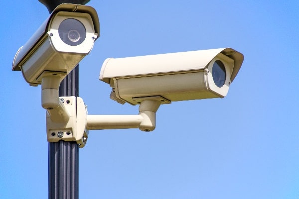 two security cameras with blue sky in the background