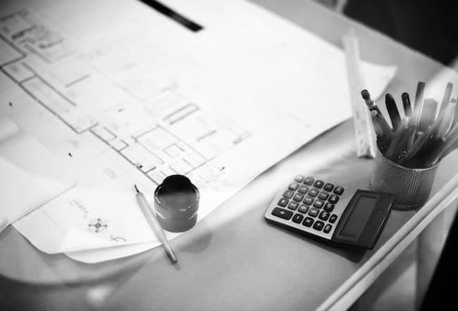 Architectural designs on desk with mug and calculator