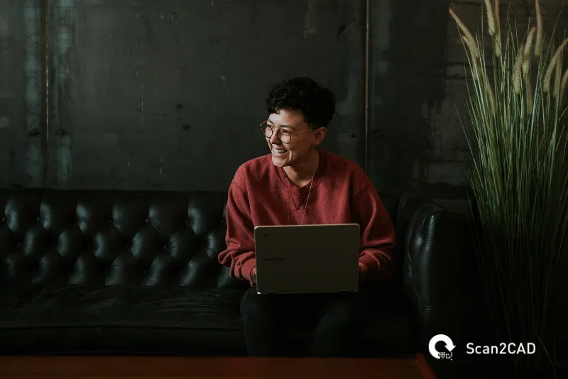 person with a laptop, smiling on a sofa